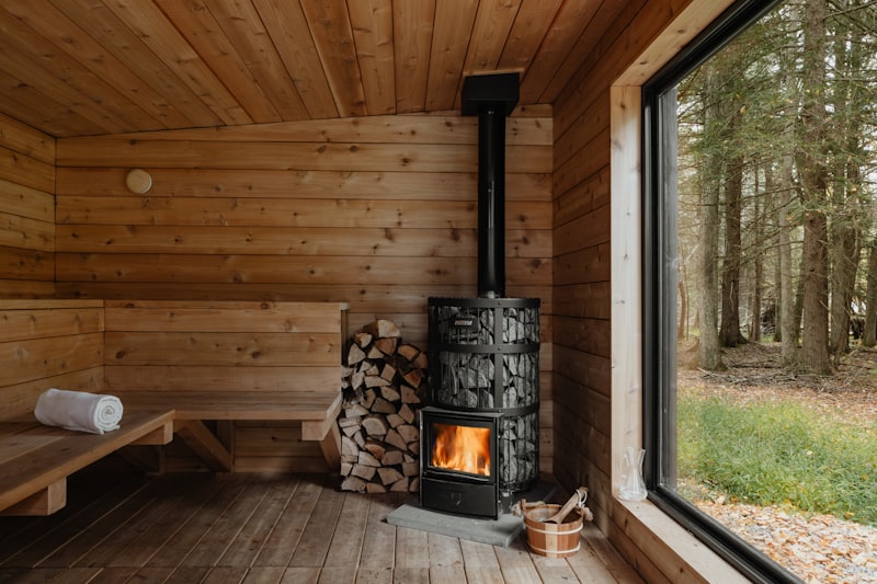 Cabin sauna with wood-burning stove and forest view through window